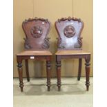 A pair of Victorian mahogany hall chairs, the shield shaped backs with carved acanthus and moulded