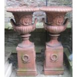 A pair of reproduction campana shaped garden urns with flared egg and dart rims, raised floral