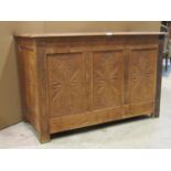 A stripped/scrubbed oak coffer with hinged lid, panelled frame and carved foliate detail