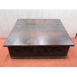 A small 18th century oak writing slope with rising lid, the front and side panels with carved and
