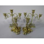 A pair of cast brass candlesticks with central floral column and three swans on a shell plateau,