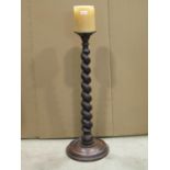A floorstanding turned oak pricket candlestick with graduated spiral twist column and moulded disc