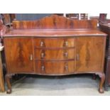 An Edwardian mahogany sideboard with shallow rail back over a serpentine front fitted with a central