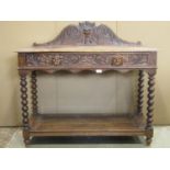 A Victorian gothic oak side table with carved acanthus and face mask detail, scrolled back, frieze