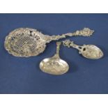 Three continental white metal novelty spoons to include a sifter spoon, the bowl with diaper