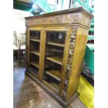 A Victorian oak cabinet enclosed by two glazed panelled doors, within a carved frame, showing fruit,