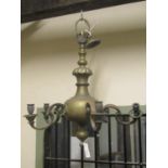A heavy Dutch style brass chandelier with five scrolling branches and candle sockets surrounding a