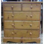 A modern pine bedroom chest of three long and two short drawers with raised associated swing