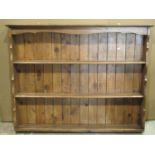 A stripped pine plate rack with open fixed shelves, shaped sides and tongue and groove boarded back,