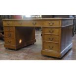 A Victorian oak pedestal writing desk fitted with an arrangement of nine drawers, with chamfered