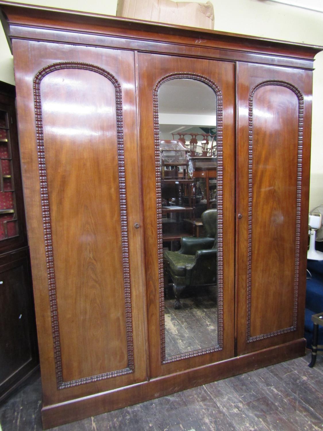 A good quality Victorian mahogany triple wardrobe, the central mirror panelled door flanked by two