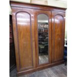 A good quality Victorian mahogany triple wardrobe, the central mirror panelled door flanked by two