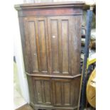 A substantial Georgian oak free standing corner cupboard enclosed by two pairs of panelled doors and