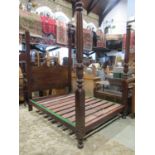 A mahogany four poster bedstead with broken swan neck panelled headboard and partially turned and