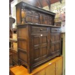 A reproduction oak court cupboard enclosed by four quarter panelled doors and two frieze drawers
