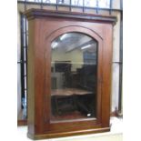 A 19th century mahogany hanging corner cupboard enclosed by an arched and glazed panelled door,