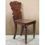 A 19th century mahogany hall chair, the shield shaped back with carved c scroll and acanthus