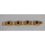 Ornate gilt metal costume bracelet set with cabochon amethyst coloured paste and faux pearls, 23cm
