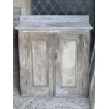 An old pine side cupboard enclosed by a pair of rectangular moulded panelled doors flanked by