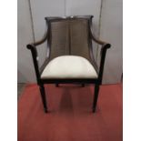 A late 19th century century bergere armchair, in the Georgian manner, with scrolled arms, rasied