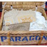 Large wicker storage hamper containing vintage table linen, some with drawn thread work and