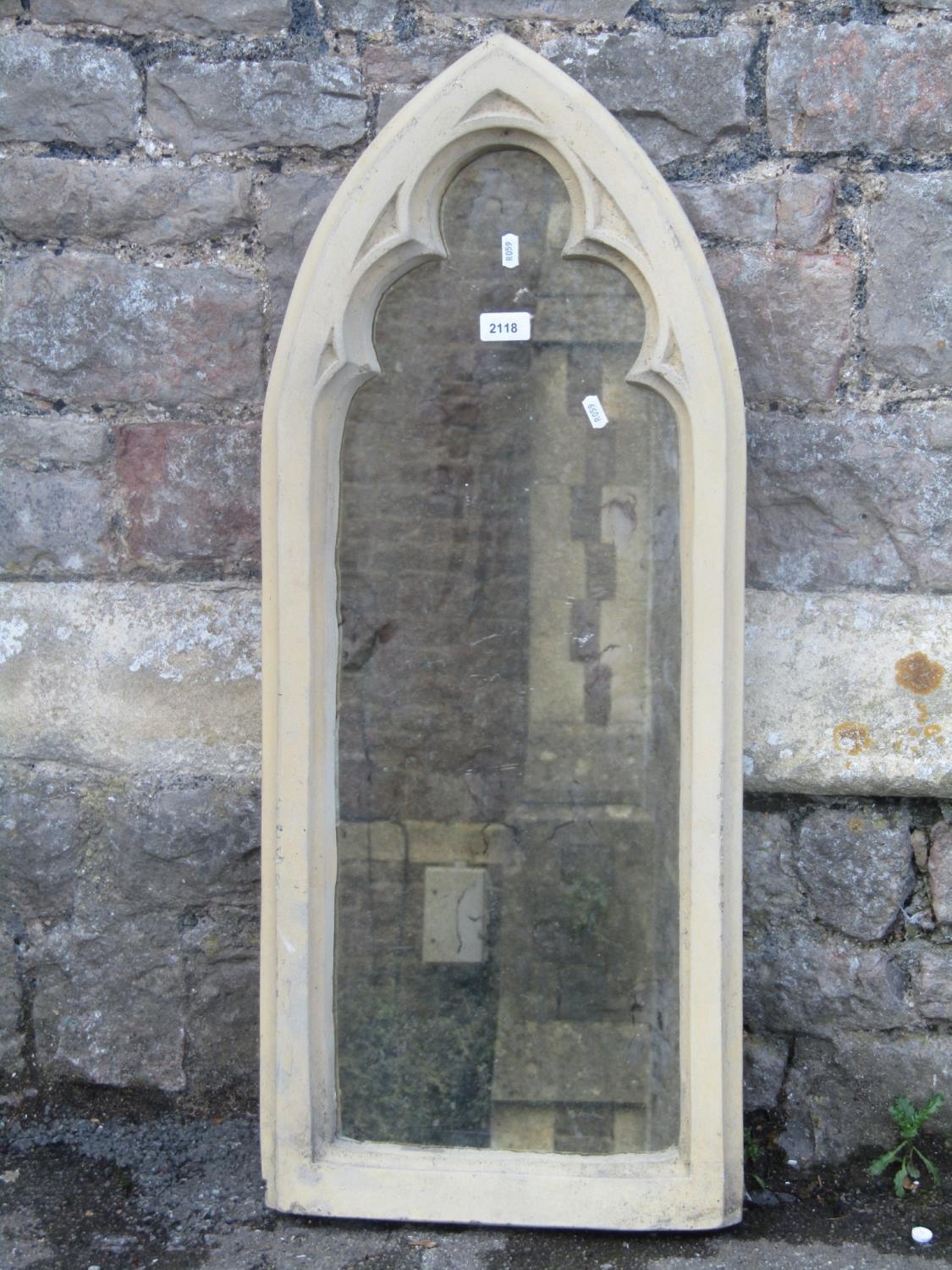 A novel contemporary wall mirror in the form of a lancet shaped gothic window enclosing a distressed