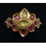 A YELLOW METAL RING, SET WITH SEVEN FREE-FORM CABOCHON RUBIES (TWO STONES MISSING), IN A CLOSED BACK