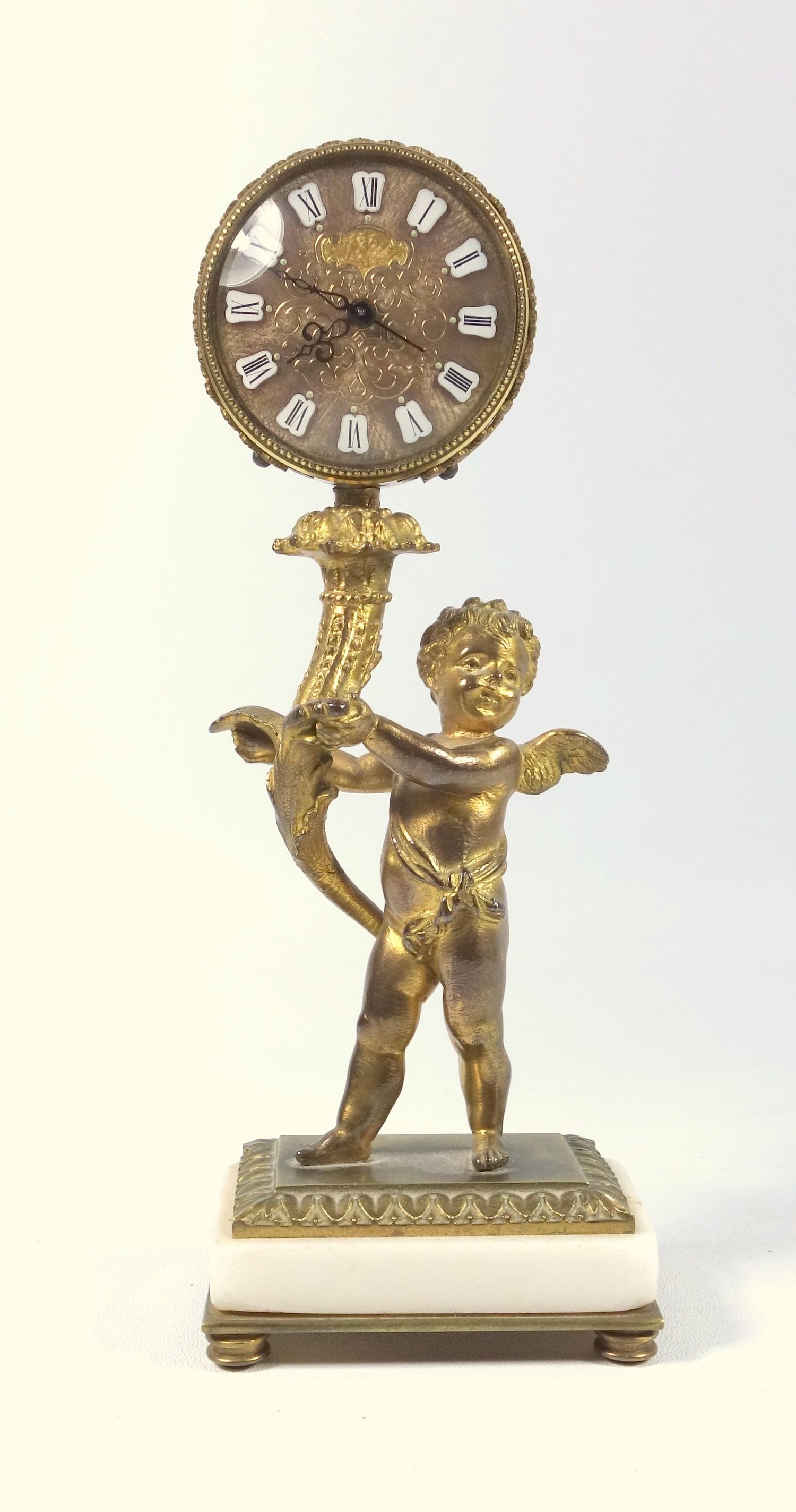 FRENCH GILT BRONZE ALARM CLOCK WITH A CHERUB HOLDING A CORNUCOPIA SUPPORTING A CIRCULAR DIAL