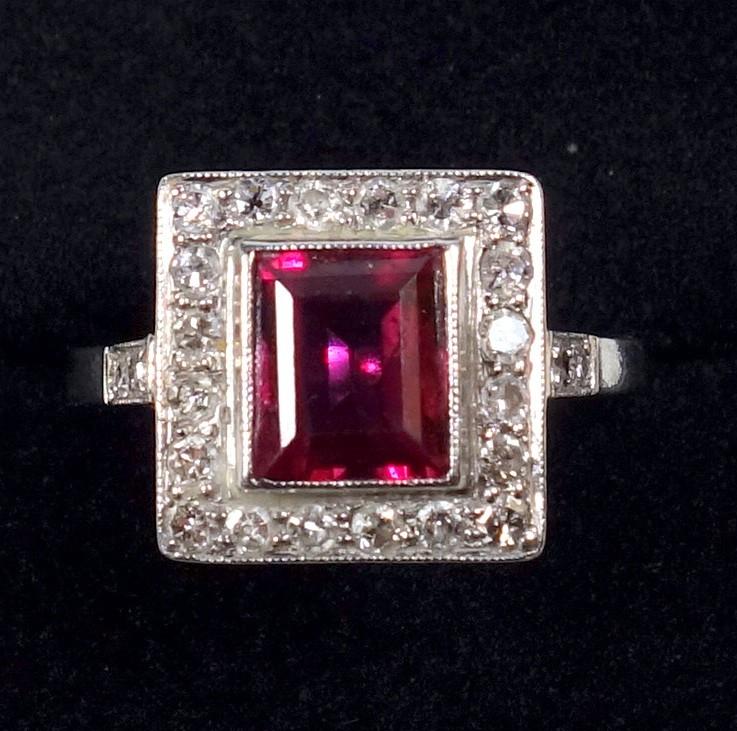 WHITE METAL RING SET RECTANGULAR CUT RUBY STONE 7 X 6 MM AND TWENTY FOUR DIAMONDS, STAMPED 'PLAT',