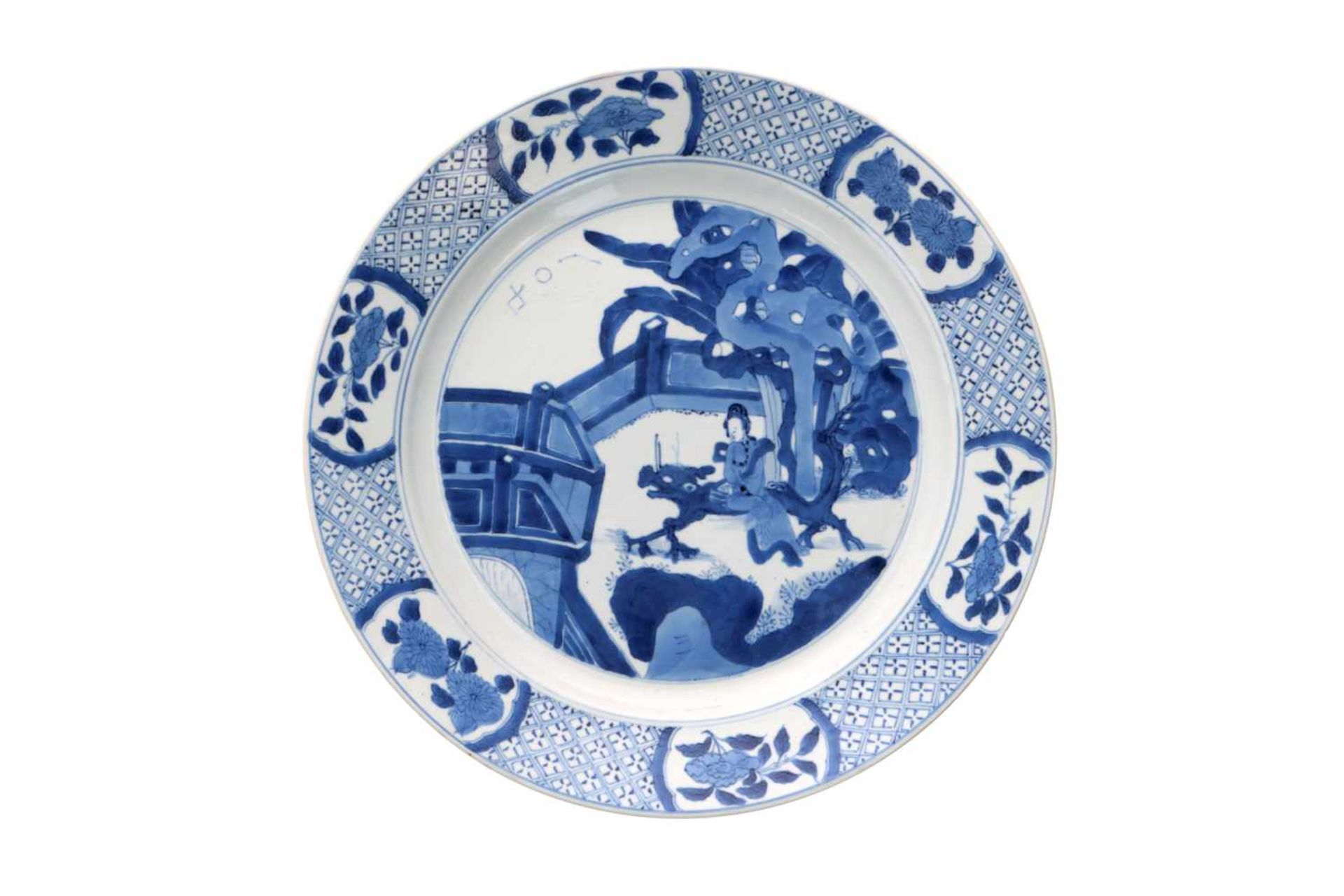 A blue and white porcelain dish, decorated with long Eliza on a bench in a garden. Marked with 6-