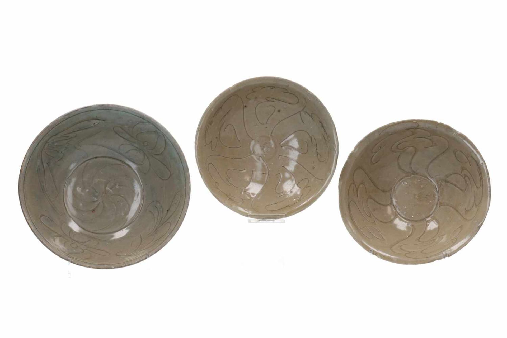 Lot of three celadon glazed bowls with abstract decor of clouds or flowers. Unmarked. China, Song.