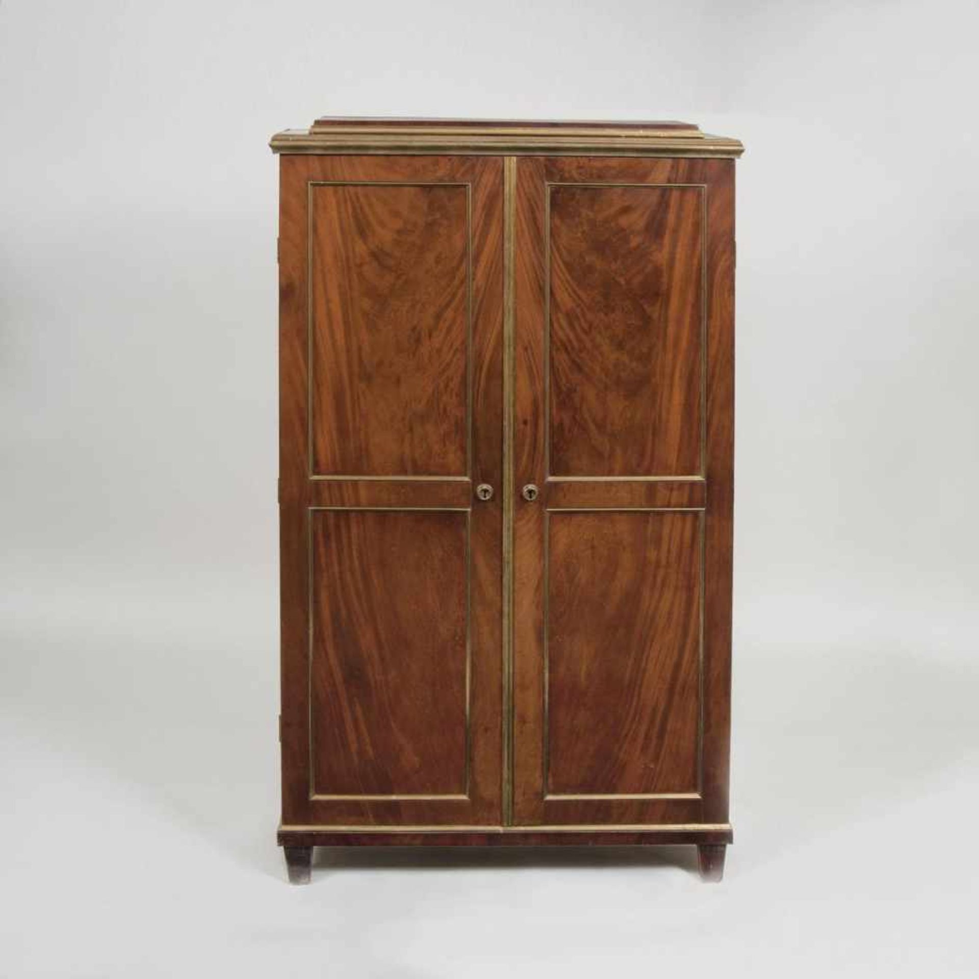 An Empire CabinetFrance early 19th cent. Mahogany, veneered, brass. Two doors, structured by brass