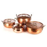 A SET OF FOUR LIDDED 'ANTELOPE MASK' COPPER POTS In sizes, each with two copper handles issuing from