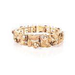 A GOLD AND DIAMOND BRACELET Designed as a tapered band of fower heads and leaves highlighted with