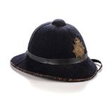 A SOUTH AFRICAN POLICE FORCE PITH HELMET, 1950s Size seven, black cloth, with large brass helmet