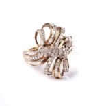 A DIAMOND DRESS RING Of cross-over ribbon design, centred with three flower head cluster motifs,