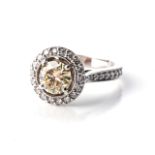 A DIAMOND HALO RING Claw-set to the centre with a round, brilliant-cut diamond weighing 1,37cts,