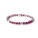 A RUBY AND DIAMOND TENNIS BRACELET Claw-set with 32 round, brilliant-cut rubies, weighing