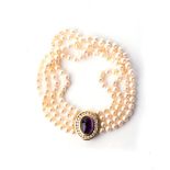 A MULTI-STRAND PEARL NECKLACE Bezel-set to the centre with an oval cabochon amethyst, 20mm long,