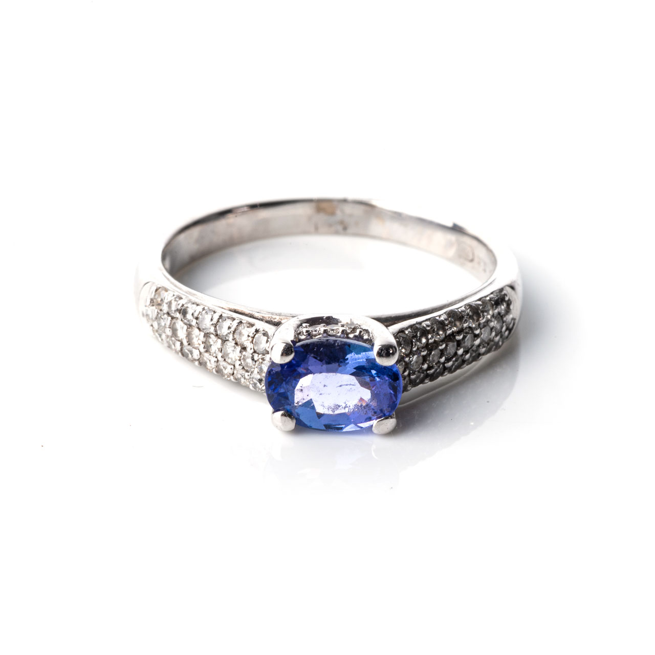 A TANZANITE AND DIAMOND RING Claw-set to the centre, with an oval-cut tanzanite weighing