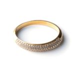 A GOLD BANGLE Pavé-set to the top with 109 round brilliant-cut diamonds with a combined weight of