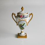 A CERAMIC URN AND COVER Two handled urn with lid, gold with floral design, on square base, 15cm high