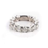 A DIAMOND ETERNITY RING Claw set with seventeen round brilliant-cut diamonds weighing