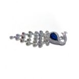 A SILVER BROOCH stylised as a peacock, claw set to the top with a created sapphire surrounded by