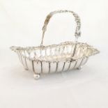 AN ELECTROPLATE CAKE BASKET Oval, pierced bail handle above a foliate embossed rim, gadrooned