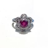 A RUBY AND DIAMOND RING claw set to the centre with a round brilliant cut ruby weighing