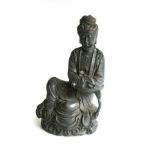 A CHINESE BRONZE FIGURE OF GUAN-YIN Seated on a rocky outcrop in 'royal ease', the figure clad in
