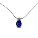 A TANZANITE AND DIAMOND PENDANT claw set to the centre with an oval cut tanzanite accompanied by a