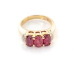 A RUBY AND DIAMOND RING claw set to the centre with tree oval rubies with a combined weight of