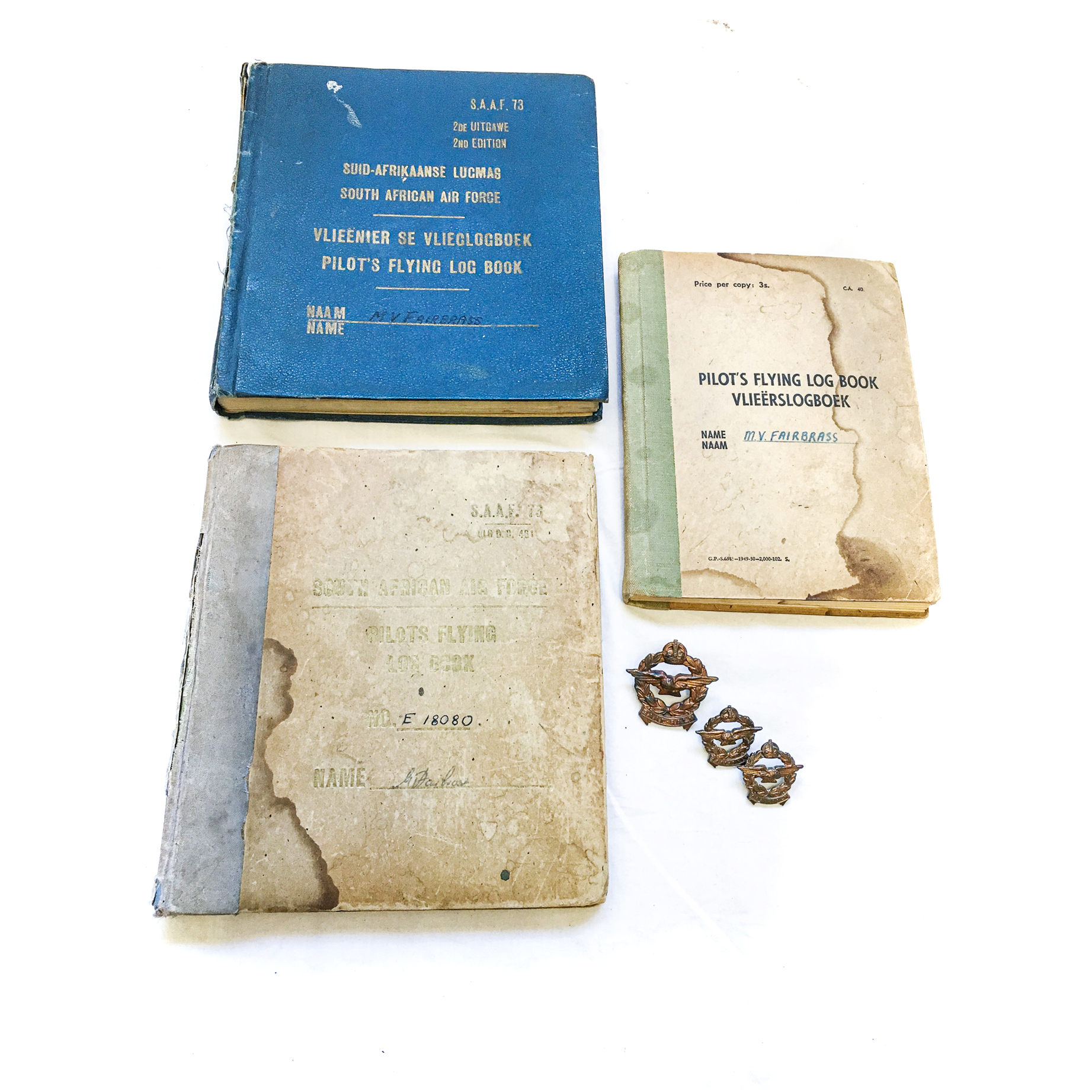 A SAAF PILOT'S LOG BOOKS AND BADGE SET SAAF named Pilot set of 3 log books for a 40 Squadron pilot